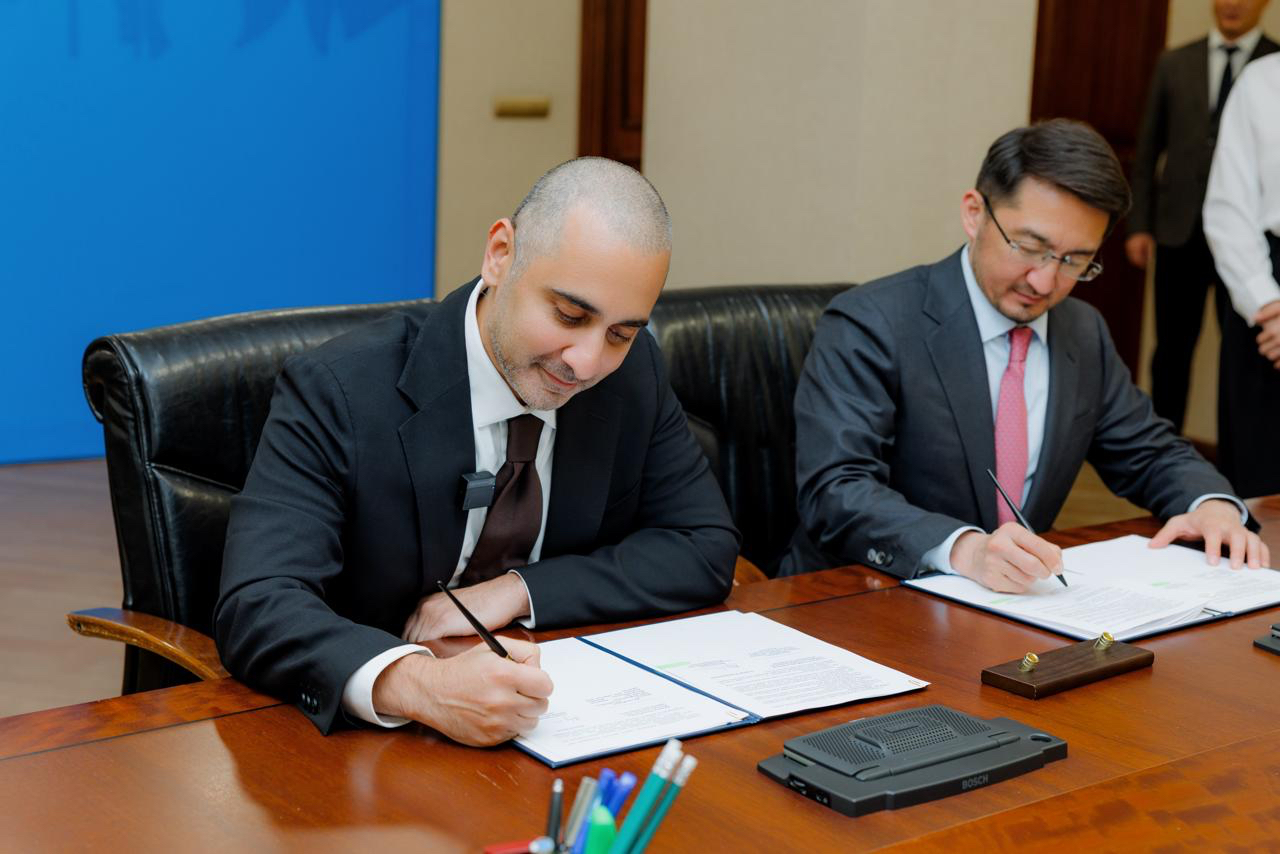 Balaji Srinivasan signing a memorandum of understanding at a formal table in Kazakhstan